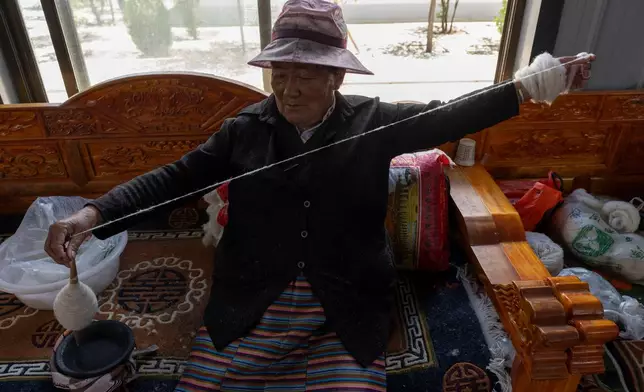 A worker pulls wool into a yarn at the Ethnic Huaji Handwoven Cooperative in Shannan in western China's Tibet Autonomous Region on July 23, 2026, as seen during a government organized visit for foreign journalists. (AP Photo/Ng Han Guan)