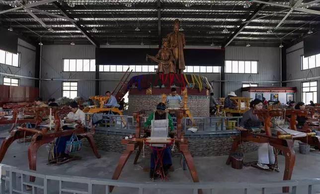 Workers weave Pulu, a traditional wooden fabric into clothing, at wooden looms near statues of Princess Wencheng and Tibetan King Songtsen Gampo at the Ethnic Huaji Handwoven Cooperative in Shannan in western China's Tibet Autonomous Region on July 23, 2026, as seen during a government organized visit for foreign journalists. (AP Photo/Ng Han Guan)