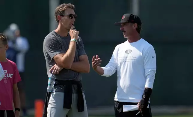 San Francisco 49ers head coach Kyle Shanahan, right, talks to Golden State Warriors gneral manager Mike Dunleavy Jr., during a joint NFL training camp practice with the Tennessee Titans Tuesday, Aug. 11, 2026, in Santa Clara, Calif. (AP Photo/Jeff Chiu)