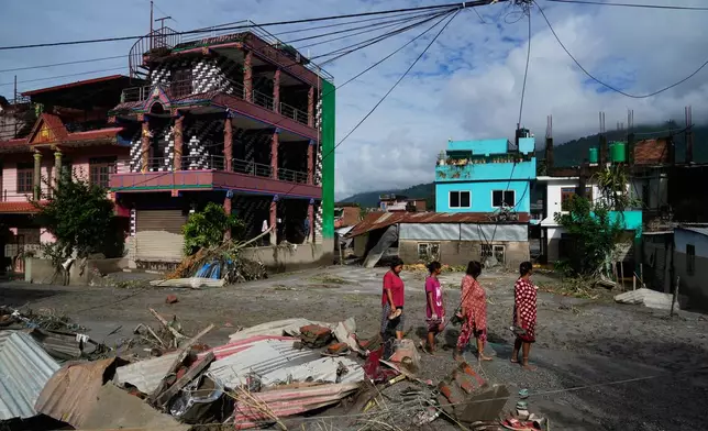 People walk past damage in the aftermath of flash floods in Devighat in the Nuwakot district in Nepal, Thursday, Aug. 27, 2026. (AP Photo/Niranjan Shrestha)
