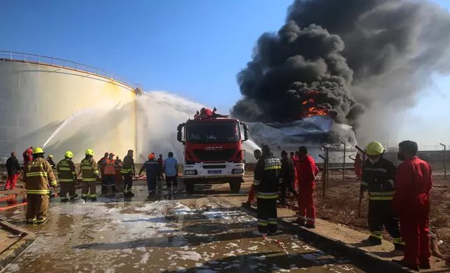 Firefighters work to contain a fire at the Zawiya oil refinery following a drone strike in Zawiya, Libya, Tuesday, Aug. 11, 2026. (AP Photo/Yousef Murad)