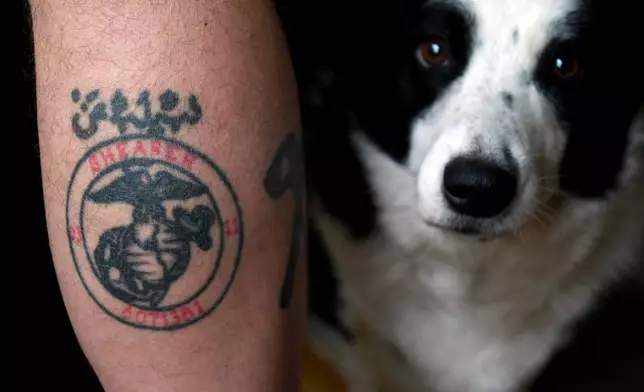Joe Shearer, who was diagnosed with traumatic brain injuries from fighting in Iraq in 2005, shows his U.S. Marine Corps leg tattoo next to his dog Desmond, at his home in Colorado Springs, Colo., on Wednesday, Aug. 5, 2026. (AP Photo/Thomas Peipert)