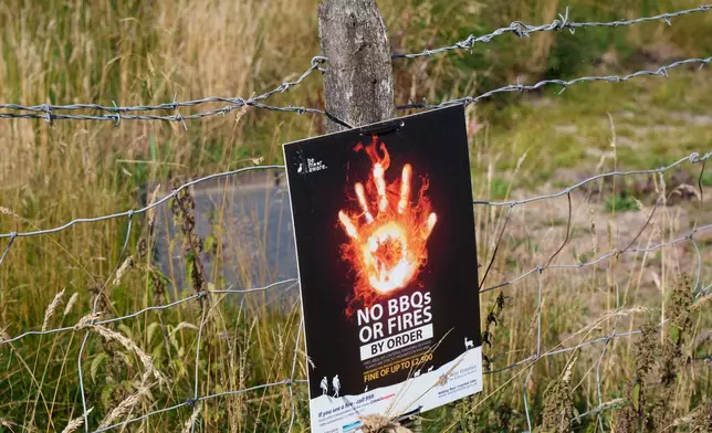 A safety signage to avoid fires is seen at Baitings reservoir near Sowerby Bridge as water levels drop throught the country, in Sowerby Bridge, England, Thursday, Aug. 13, 2026. (AP Photo/Jon Super)