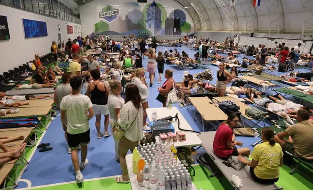 Residents and tourists evacuated from a wildfire gather inside a sports hall in Omis, southern Croatia early Friday, Aug. 14, 2026. (AP Photo/Jakov Prkic)