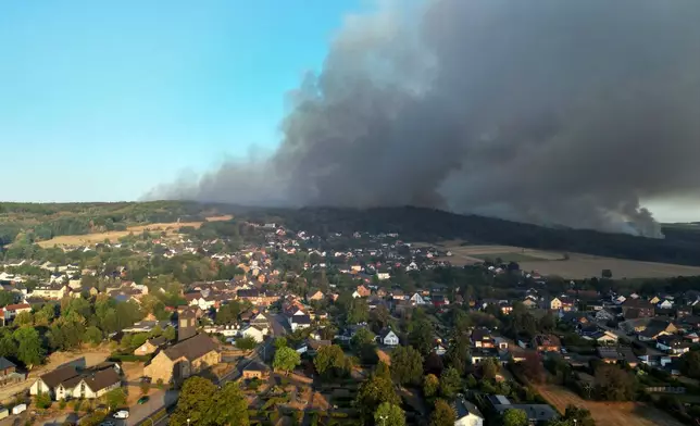 Thick smoke drifts over the Gey district from a forest fire in Hürtgenwald, Germany, Friday, Aug. 14, 2026. (Federico Gambarini/dpa via AP)
