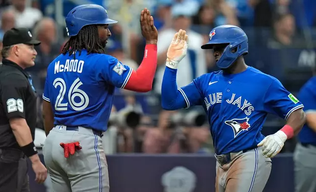 Toronto Blue Jays' Daz Cameron and Charles McAdoo (26) celebrate after scoring on a two-run single by George Springer off Tampa Bay Rays pitcher Casey Legumina during the seventh inning of a baseball game Thursday, Aug. 20, 2026, in St. Petersburg, Fla. (AP Photo/Chris O'Meara)