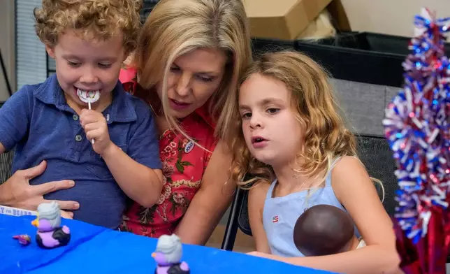 Laura Jolly, center, wife of Florida Democratic gubernatorial candidate David Jolly, amuses their children Teddy, 5 and CeCe, 7, during a town hall meeting Saturday, Aug. 8, 2026, in Leesburg, Fla. (AP Photo/John Raoux)