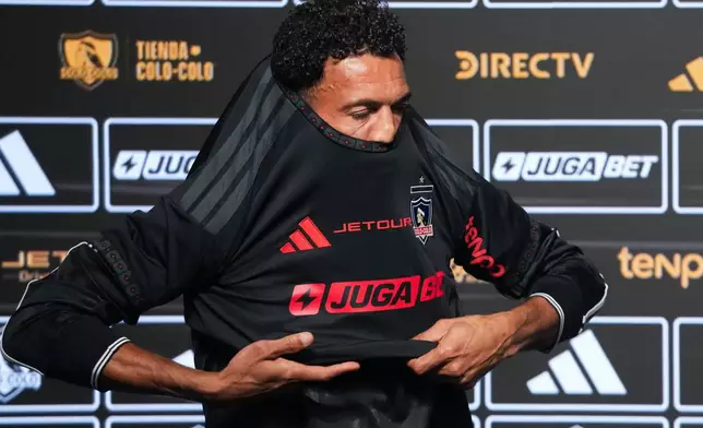 Cape Verde goalkeeper Vozinha puts on his new Colo Colo jersey during his presentation as a new player at Monumental stadium in Santiago, Chile, Tuesday, Aug. 4, 2026. (AP Photo/Esteban Felix)