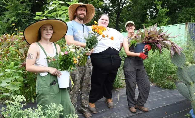 Midtown Bramble & Bloom staff, from left, Courtney Sanderson, Chase Baltz, Marisa Mender-Franklin and Mary Carnes pose with flowers gathered at a crowdsourced garden plot on Thursday, July 23, 2026 in Memphis, Tenn. (AP Photo/Kristin M. Hall)