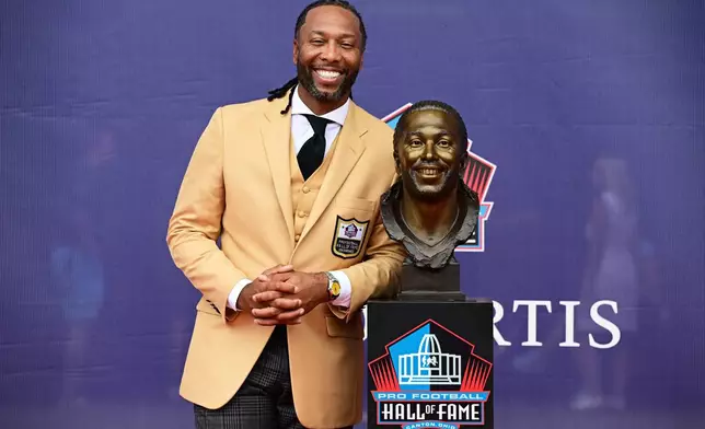 Former NFL player Larry Fitzgerald poses with his bust during the Pro Football Hall of Fame induction ceremony at the Pro Football Hall of Fame, in Canton, Ohio, Saturday, Aug. 8, 2026. (AP Photo/David Dermer)