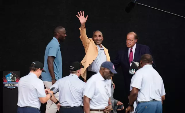 Former NFL player Roger Craig, center, waves after unveiling his bust during the Pro Football Hall of Fame induction ceremony at the Pro Football Hall of Fame, in Canton, Ohio, Saturday, Aug. 8, 2026. (AP Photo/Sue Ogrocki)