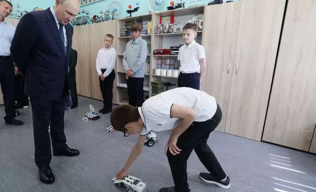 Russian President Vladimir Putin, left, interacts with schoolchildren as he visits a secondary school named after Eduard Norpolov in Kurilsk on the Iturup Island, the largest of the Kuril Islands of Russia's far-east, on Thursday, Aug. 13, 2026. (Gavriil Grigorov, Sputnik, Kremlin Pool Photo via AP)