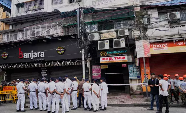 Police and volunteers of disaster management group stand outside after dousing an early morning fire at a building that housed multiple hotels and guest houses in Kolkata, India, Wednesday, Aug. 19, 2026. (AP Photo/Bikas Das)