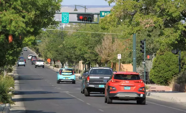 Vehicles stop along Lead Avenue where stoplights are set for a specific speed limit as part of the "rest on red" signal program in Albuquerque, N.M., Wednesday, Aug. 12, 2026. (AP Photo/Susan Montoya Bryan)