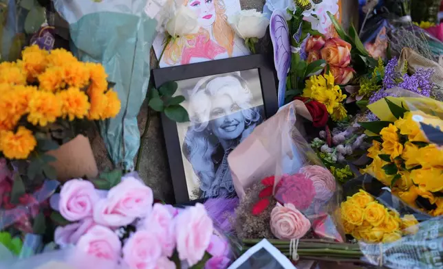 Images and flowers form a makeshift memorial honoring Dolly Parton in front of her statue in Sevierville, Tenn., Tuesday, Aug. 25, 2026. (AP Photo/Camden Hall)