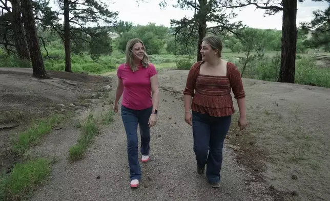 Anne Schultz and her daughter, Charlotte Touzalin, go on a walk Friday, July 10, 2026 in Elizabeth, Colo. (AP Photo/Brittany Peterson)