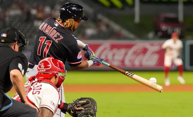 Cleveland Guardians' José Ramírez, right, hits an RBI double as Los Angeles Angels catcher Moisés Ballesteros, center, and home plate umpire Doug Eddings watch during the 10th inning of a baseball game Tuesday, Aug. 25, 2026, in Anaheim, Calif. (AP Photo/Mark J. Terrill)