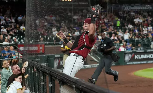 Arizona Diamondbacks catcher James McCann, center, makes a foul ball catch against San Diego Padres' Fernando Tatis Jr. as home plate umpire umpire James Jean looks on during the first inning of a baseball game, Wednesday, Aug. 5, 2026, in Phoenix. (AP Photo/Ross D. Franklin)