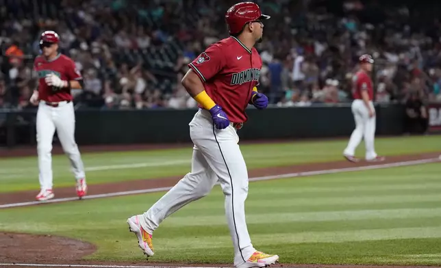Arizona Diamondbacks' Gabriel Moreno, right, jogs to first base after earning a bases loaded walk as Diamondbacks' Lars Nootbaar, left, comes in to score a run against the San Diego Padres during the fourth inning of a baseball game, Wednesday, Aug. 5, 2026, in Phoenix. (AP Photo/Ross D. Franklin)