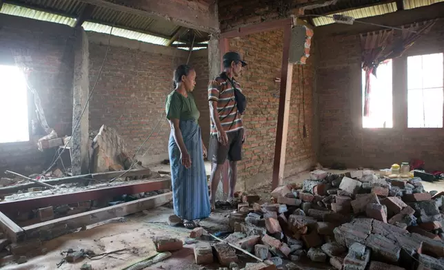 Stefanus Sailon, right, and his wife Sisilia Ilus inspect their house which was damaged during an earthquake in Mbeliling, East Nusa Tenggara province, Indonesia, Sunday, Aug. 16, 2026. (AP Photo/Firdia Lisnawati)