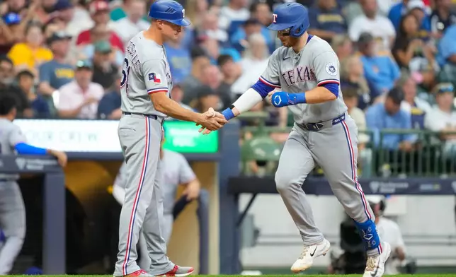 Texas Rangers' Danny Jansen, right, greets third base coach Corey Ragsdale, left, after hitting a home run during the third inning of a baseball game against the Milwaukee Brewers, Friday, Aug. 28, 2026, in Milwaukee. (AP Photo/Kayla Wolf)
