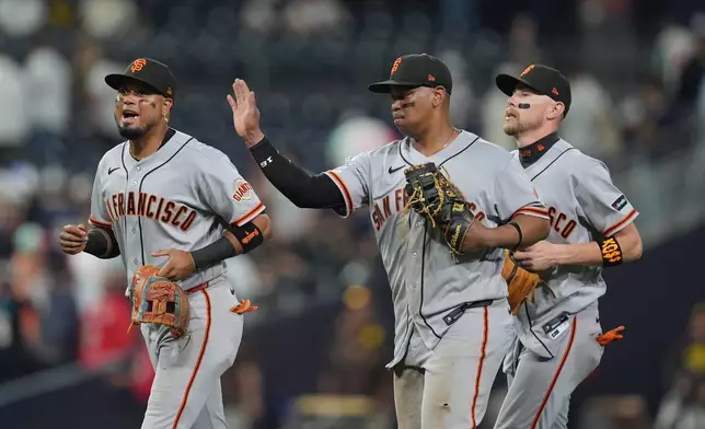 San Francisco Giants first baseman Rafael Devers, center, celebrates with teammates second baseman Luis Arraez, left, and third baseman Christian Koss after the Giants defeated the San Diego Padres 4-1 in a baseball game Thursday, July 30, 2026, in San Diego. (AP Photo/Gregory Bull)