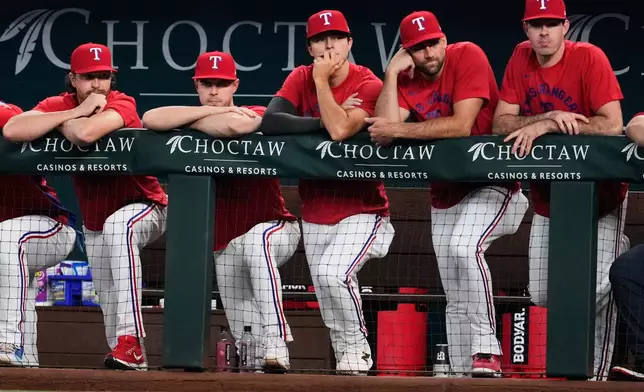 Texas Rangers' Jacob Degrom, from left, MacKenzie Gore, Jack Leiter, Nathan Eovaldi and Cody Bradford, right, stand in the dugout watching play against the San Francisco Giants in the first inning of a baseball game in Arlington, Texas, Monday, Aug. 3, 2026. (AP Photo/Tony Gutierrez)