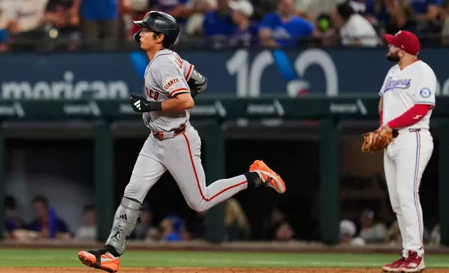 San Francisco Giants' Jung Hoo Lee, left, rounds the bases past Texas Rangers' Jake Burger, right, after Lee hit a solo home run in the third inning of a baseball game in Arlington, Texas, Monday, Aug. 3, 2026. (AP Photo/Tony Gutierrez)