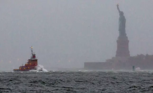 FILE - Waves crash over the bow of a tug boat as it passes near the Statue of Liberty in New York as rough water as the result of Hurricane Sandy churns the waters of New York Harbor, Oct. 29, 2012. (AP Photo/Craig Ruttle, File)