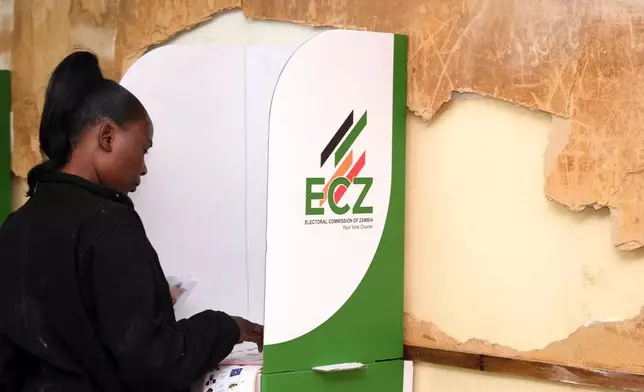 A woman is seen in a voting booth at a polling station in Lusaka, Zambia, Thursday, Aug. 13, 2026. (AP Photo/Anita Reed)