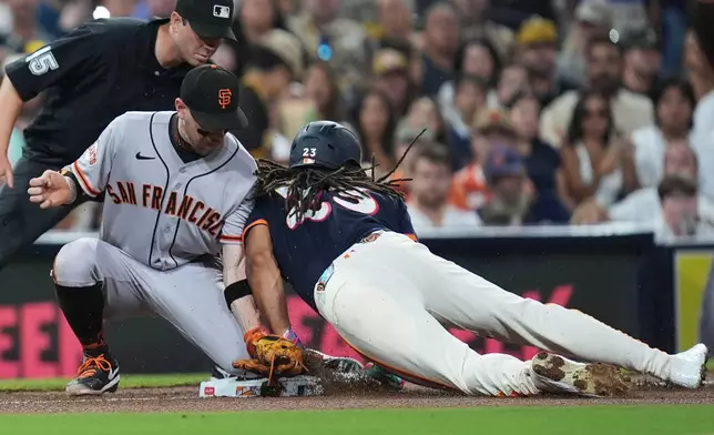 San Diego Padres' Fernando Tatis Jr., right, steals third base as San Francisco Giants third baseman Christian Koss is late with the tag during the fourth inning of a baseball game Friday, July 31, 2026, in San Diego. (AP Photo/Gregory Bull)