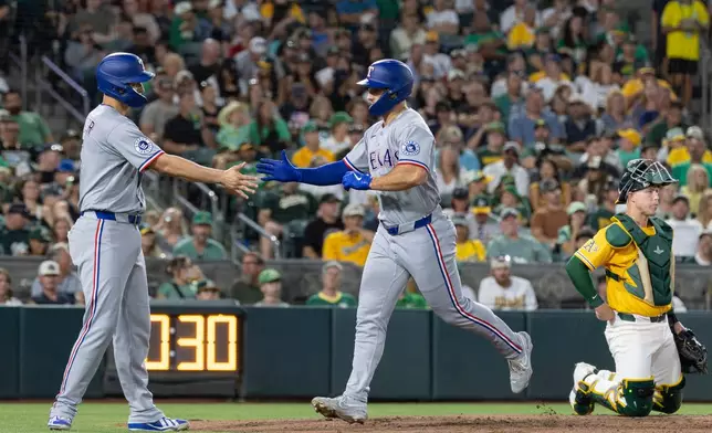 Texas Rangers' Wyatt Langford, right, high-fives Corey Seager after hitting a two-run home run during the sixth inning of a baseball game against the Athletics Saturday, Aug. 15, 2026, in West Sacramento, Calif. (AP Photo/Sara Nevis)