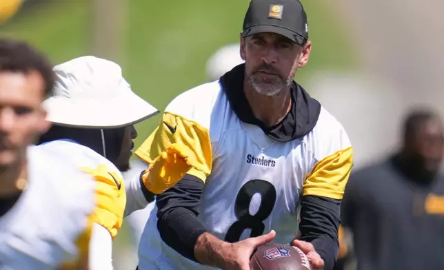 Pittsburgh Steelers quarterback Aaron Rodgers (8) hands off to running back Rico Dowdie during the team's NFL football training camp in Latrobe, Pa., on Friday, July 31, 2026.(AP Photo/Gene J. Puskar)