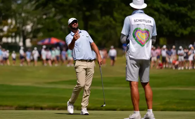 Scottie Scheffler tosses his ball to his cadie on the 11th green during the final round of the St. Jude Championship golf tournament, Sunday, Aug. 16, 2026, in Memphis, Tenn. (AP Photo/George Walker IV)