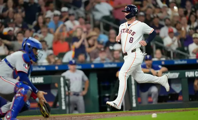 Houston Astros' Christian Walker (8) scores as Texas Rangers catcher Elias Díaz handles the throw during the third inning of a baseball game Saturday, Aug. 1, 2026, in Houston. (AP Photo/David J. Phillip)