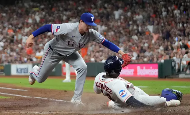 Houston Astros' Yordan Alvarez (44) scores on a wild pitch by Texas Rangers pitcher Cole Winn, left, during the fourth inning of a baseball game Saturday, Aug. 1, 2026, in Houston. (AP Photo/David J. Phillip)