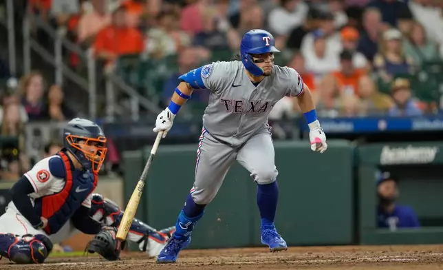 Texas Rangers' Alejandro Osuna, right, watches his RBI single in front of Houston Astros catcher Yainer Diaz during the fourth inning of a baseball game Saturday, Aug. 1, 2026, in Houston. (AP Photo/David J. Phillip)