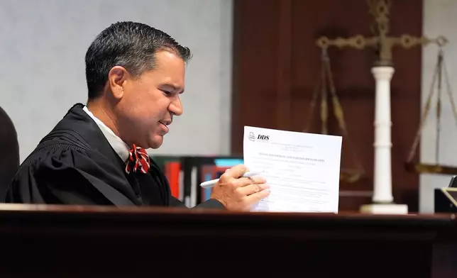 Judge Jason B. Thompson holds up a piece of paper during comedian and actor Tiffany Haddish’s court appearance via Zoom Tuesday, Aug. 11, 2026, in Fayetteville, Ga. (AP Photo/Brynn Anderson)