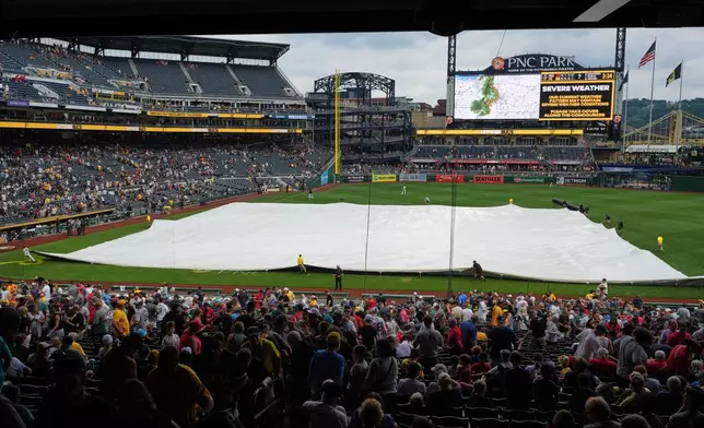 The grounds crew at PNC Park deploys a tarp in preparation for severe weather during a baseball game between the Pittsburgh Pirates and the Boston Red Sox in Pittsburgh, Sunday, Aug. 16, 2026. (AP Photo/Gene J. Puskar)