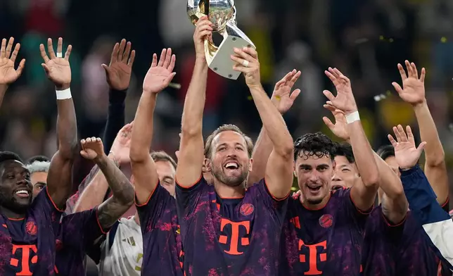 Bayern's Harry Kane holds the trophy after winning the Franz Beckenbauer German Supercup soccer match between Borussia Dortmund and Bayern Munich in Dortmund, Germany, Saturday, Aug. 22, 2026. (AP Photo/Martin Meissner)
