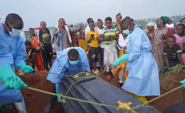 People dressed in protective gear lower into a grave the coffin containing the remains of Jeannine Katusabe, who died of Ebola, during a burial service in Bunia, Ituri province, eastern Congo, Tuesday, Aug. 11, 2026. (AP Photo/Dieudonne Dirole)