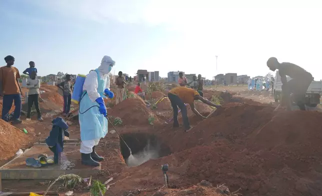 A health worker sprays disinfectant in a freshly dug grave for the body of Jacques Lobo Dhena, who died of Ebola, in Bunia, Ituri province, eastern Congo, Wednesday, Aug. 12, 2026. (AP Photo/Dieudonne Dirole)
