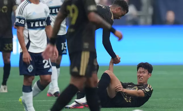 Los Angeles FC's Son Heung-min, right, is helped up by teammate Timothy Tillman after a collision with Vancouver Whitecaps' Mathias Laborda, not seen, during the first half of an MLS soccer match, in Vancouver, on Saturday, August 1, 2026. (Darryl Dyck/The Canadian Press via AP)