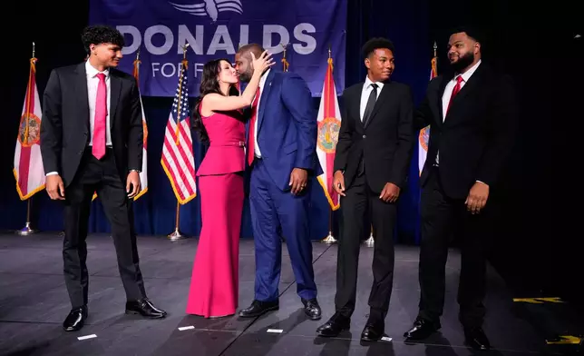 Florida Republican gubernatorial candidate Byron Donalds, center, is kissed by his wife Erika, while standing on stage with their children Darin, left, Damon, second from left, and Mason during at a primary election party Tuesday, Aug. 18, 2026, in Orlando, Fla. (AP Photo/John Raoux)