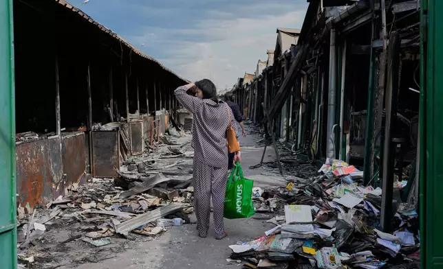 A woman reacts as she looks at charred books after a fire at the country's biggest book market, caused by a recent Russian missile attack, in Kyiv, Ukraine, Wednesday, Aug. 19, 2026. (AP Photo/Efrem Lukatsky)