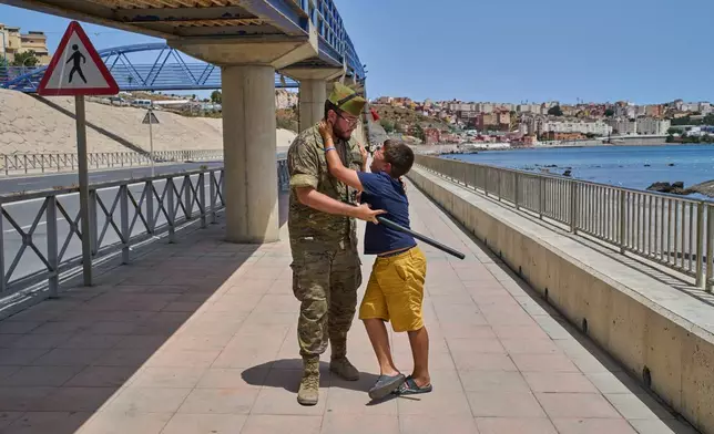 A 12-year-old unaccompanied minor who crossed into Spain is escorted by a Spanish soldier to the Spain-Morocco border as the child begs not to be sent back to Morocco from the Spanish enclave of Ceuta, Monday, Aug. 3, 2026. The forced deportation of the unaccompanied minor was stopped by a high-ranking official a few meters before the child reached the border after residents and journalists said the migrant was a minor. (AP Photo/Bernat Armangue)