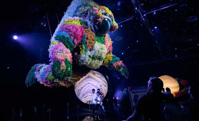 Visitors view a giant floral installation at the Flowers 2026 exhibition, in Tel Aviv, Israel, Thursday, Aug. 13, 2026. (AP Photo/Oded Balilty)
