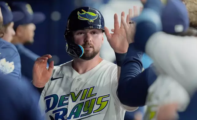 Tampa Bay Rays' Liam Hicks celebrates in the dugout after scoring on an RBI double by Richie Palacios off Baltimore Orioles pitcher Chris Bassitt during the second inning of a baseball game Friday, Aug. 14, 2026, in St. Petersburg, Fla. (AP Photo/Chris O'Meara)