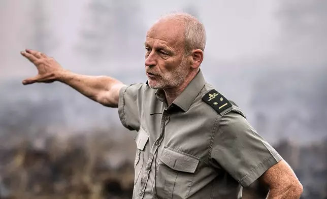 District Forestry Officer of the Haute Fagnes, Yves Pieper, speaks with the media as smoke rises from a field and forest as a wildfire burns near Waimes, Belgium, Monday, Aug. 17, 2026. (AP Photo/Valentin Bianchi)