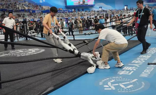 Technicians carry a robot after competing at the Free Combat event of the World Humanoid Robot Games in Beijing, Sunday, Aug. 23, 2026. (AP Photo/Achmad Ibrahim)